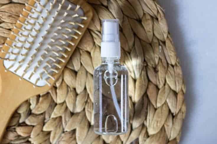 tan hair brush and glass spray bottle with essential oil hair spray