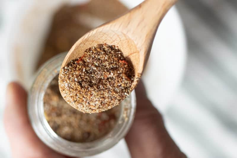 wooden spoon pouring taco seasoning in spice jar