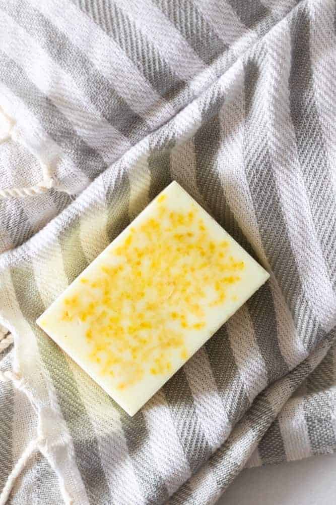 All-Natural lemon soap bar on gray and white stripe towel.