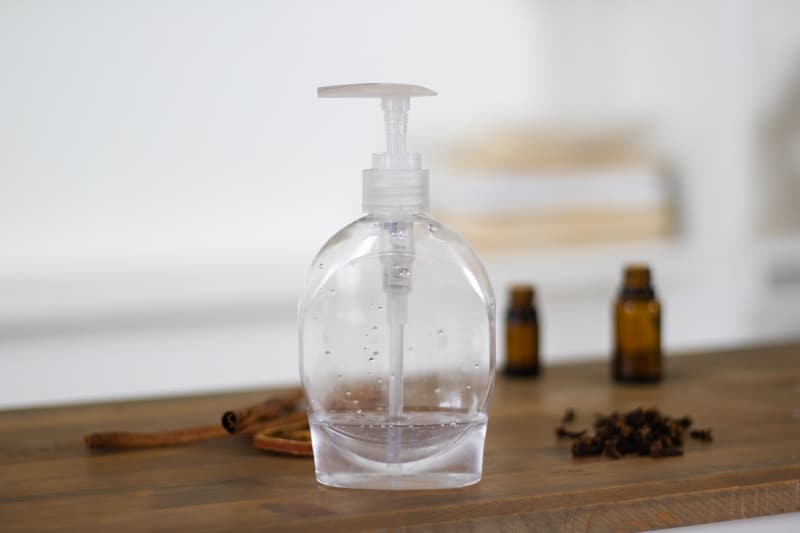 homemade hand sanitizer on table with spices and essential oil bottles