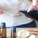 pouring homemade elderberry syrup out of mason jar onto spoon