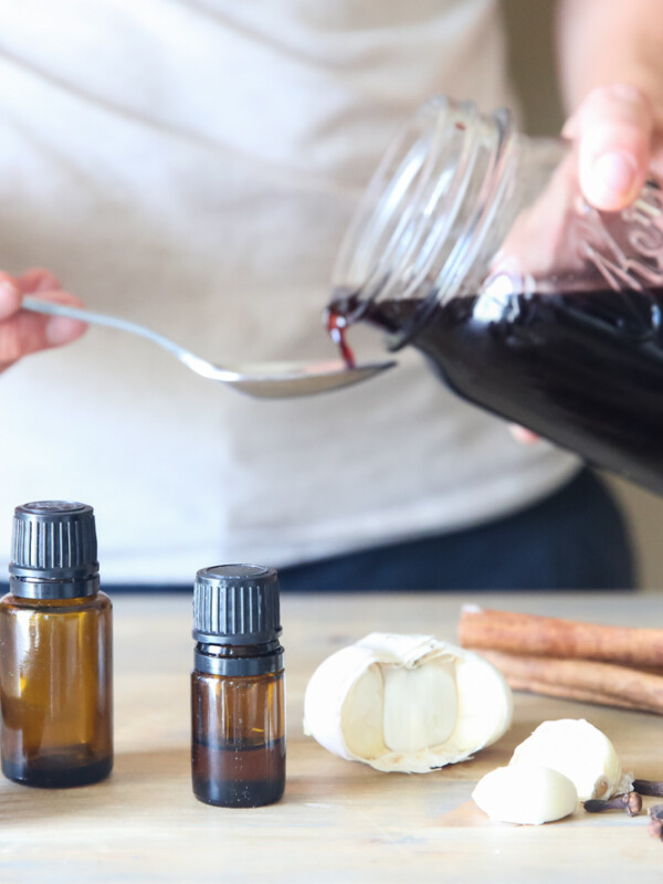 pouring homemade elderberry syrup out of mason jar onto spoon