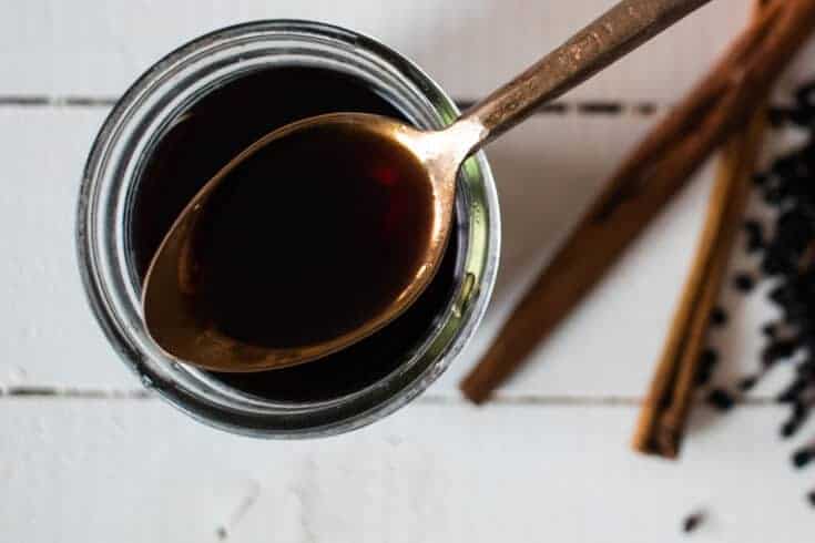 elderberry syrup on gold spoon over mason jar