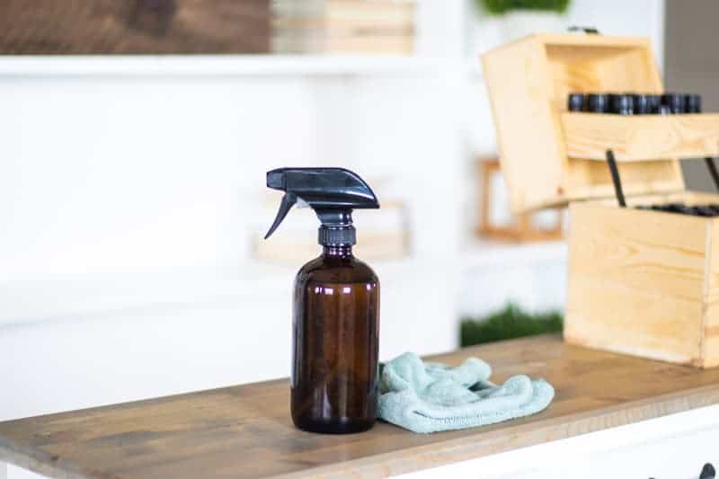 natural cleaner in glass spray bottle in front of white bookshelf