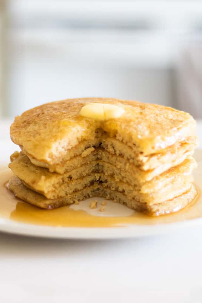 tall stack of pancakes with a bite taken out of it.