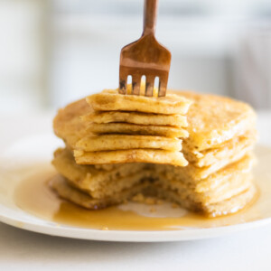 Sourdough pancakes with maple syrup in white plate.