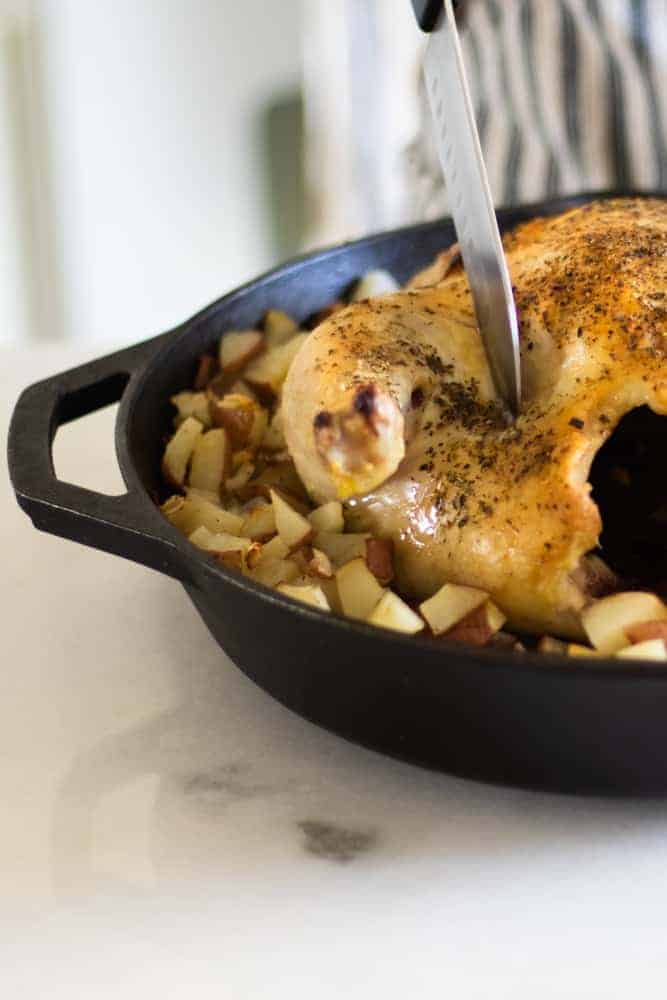 carving roasted whole chicken in a cast-iron skillet