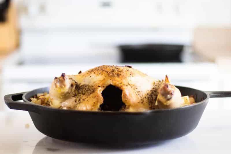 cast iron skillet with whole chicken in white kitchen