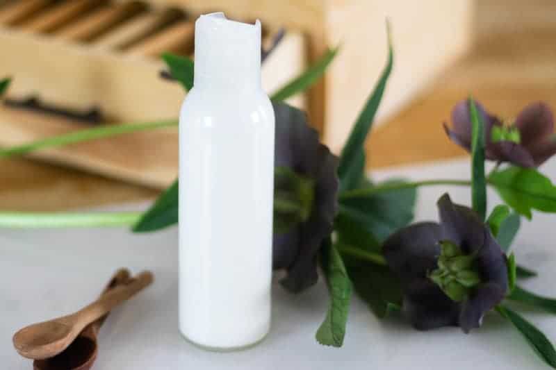 shower gel on white marble with fresh flowers in background