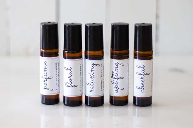 amber essential oil roller bottles with black lids and white labels on white marble countertop