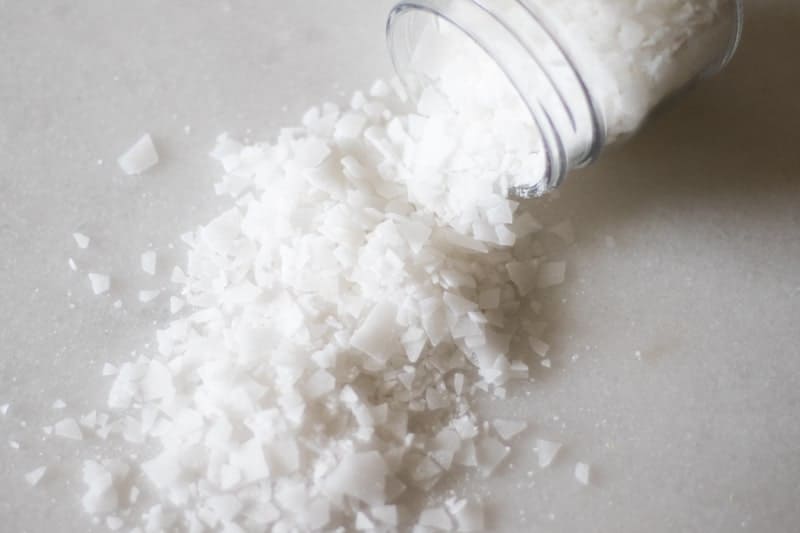 white magnesium flakes poured out from a glass mason jar on white marble