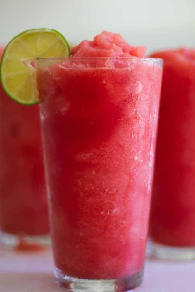 homemade watermelon slushie in 3 glasses with limes