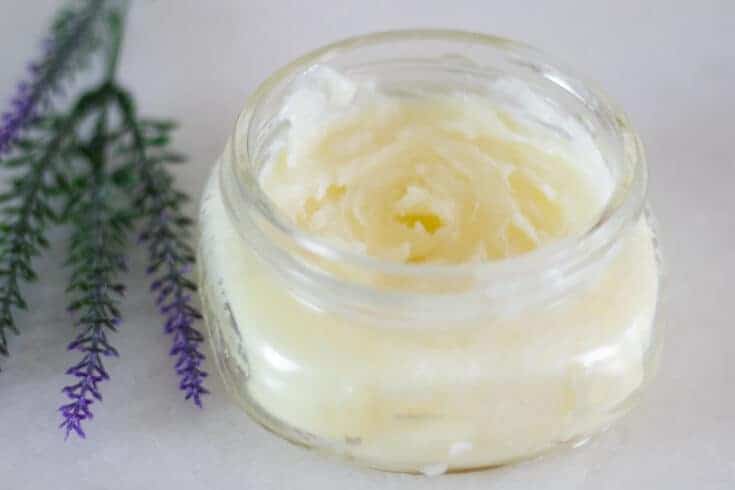 homemade burn salve in clear jar with lavender sprigs on white marble