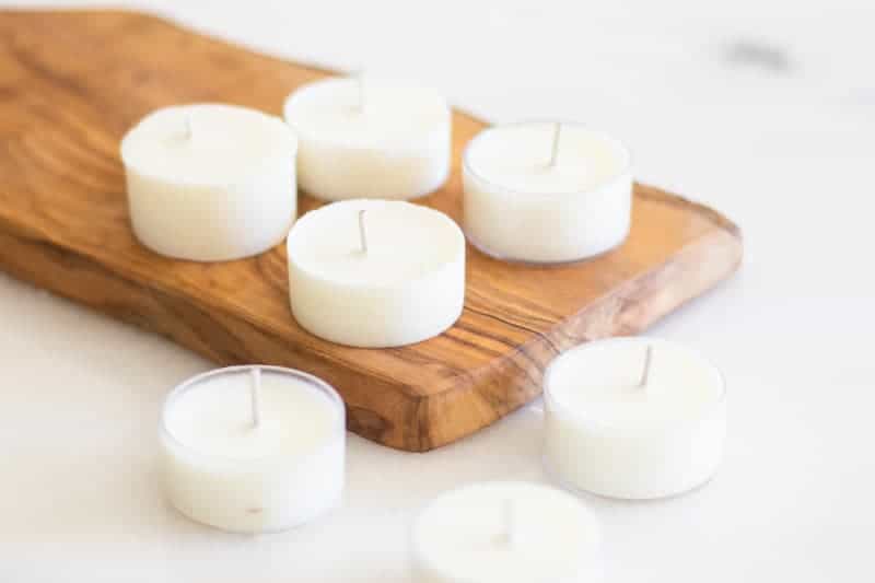 white tea light bug repellent candles on wooden cutting board.