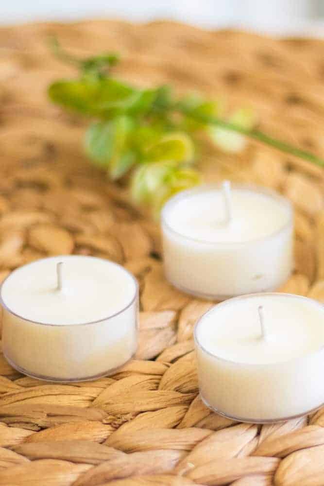 white tea light bug repellent candles on tan wicker.