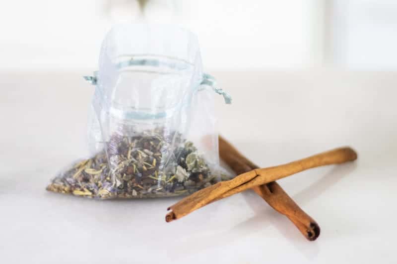 dried herbs in mesh bag with two cinnamon sticks next to it