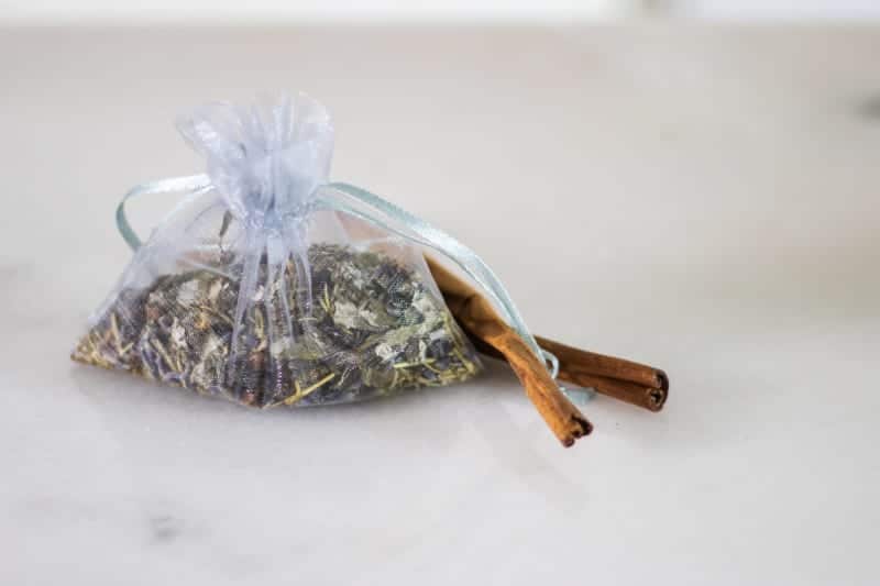 mesh bag of moth repellent with dried herbs on white marble