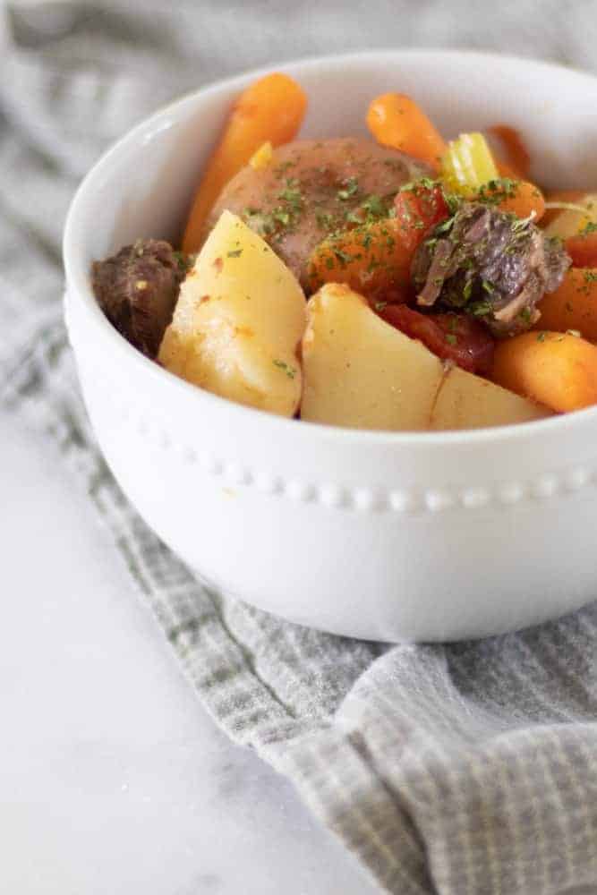 bowl of beef shank soup in white bowl on gray towel