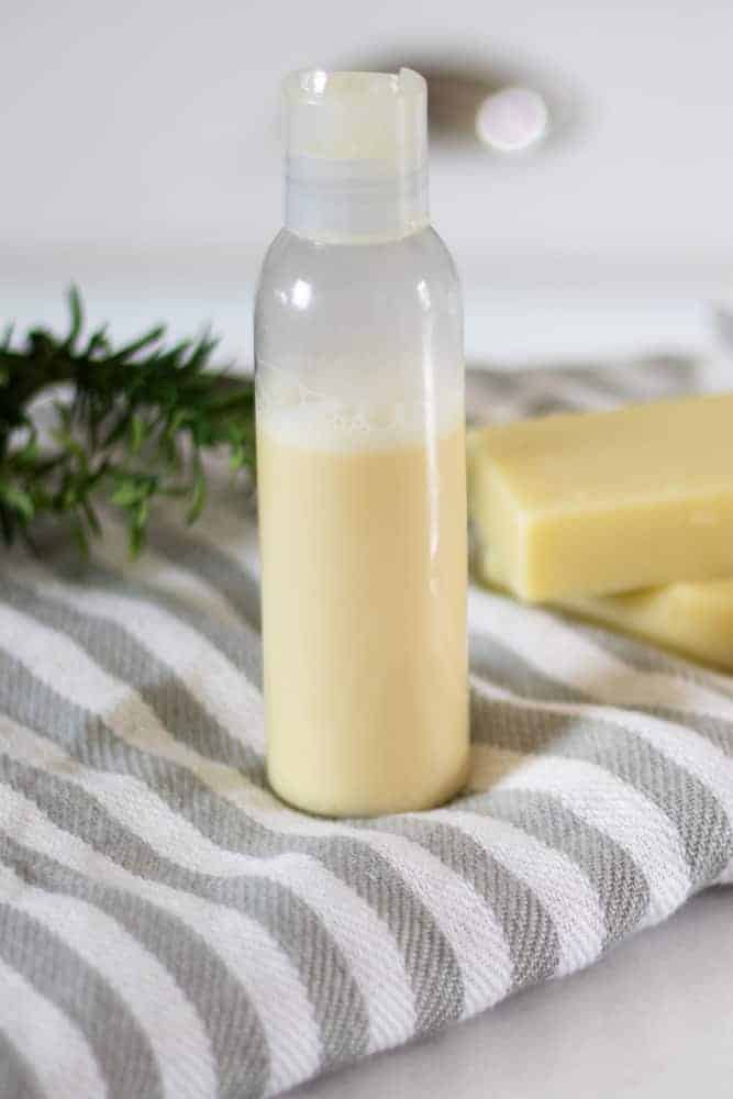 homemade shampoo in bottle sitting on white and gray striped towel