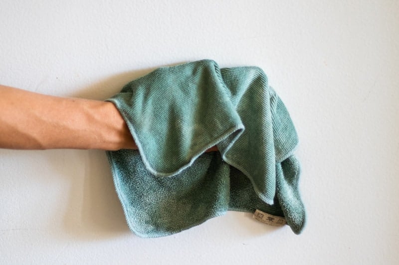 Wiping stain off white wall with green cloth