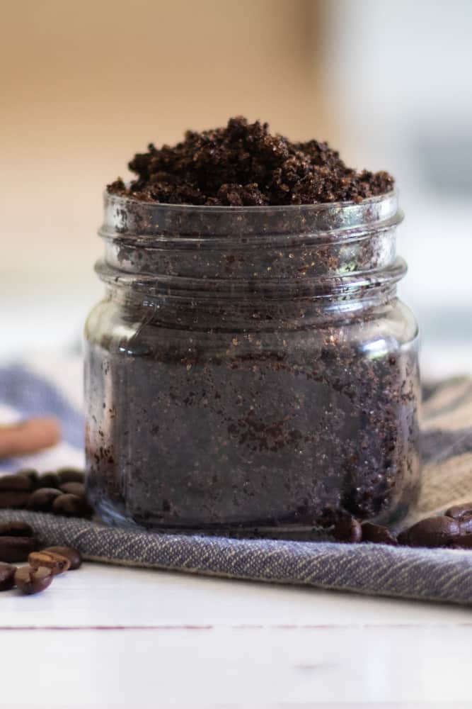 Homemade coffee scrub in widemouth mason jar on white shiplap.