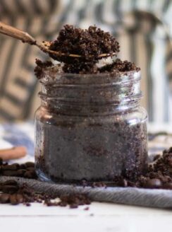 scooping out some homemade coffee scrub with a gold spoon to apply to the face.