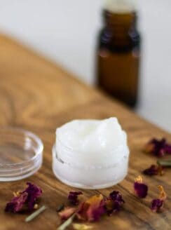 homemade eye cream on wooden board with essential oil bottle in background