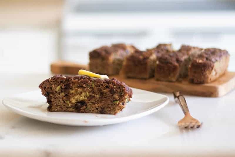 zucchini bread on white plate with a dab of butter