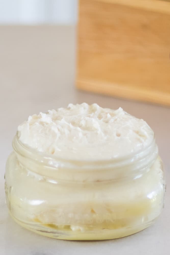 Bedtime baby lotion whipped and in a wide mouth glass jar on marble countertop.