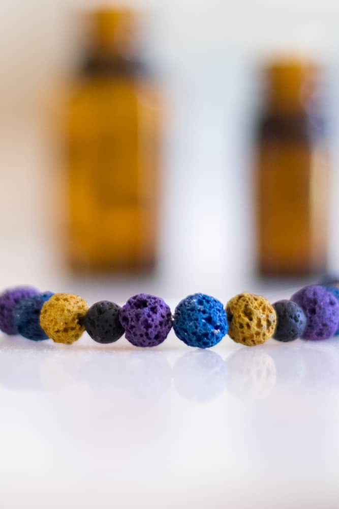 essential oil diffuser bracelet on white marble with essential oil bottles in background