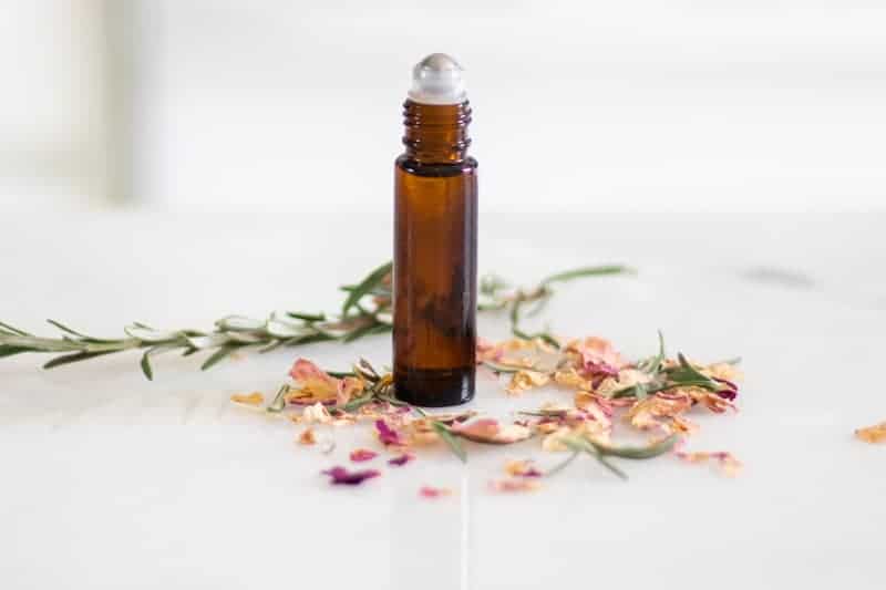 essential oil blend for acne scars with lavender sprigs and rose petals on white marble