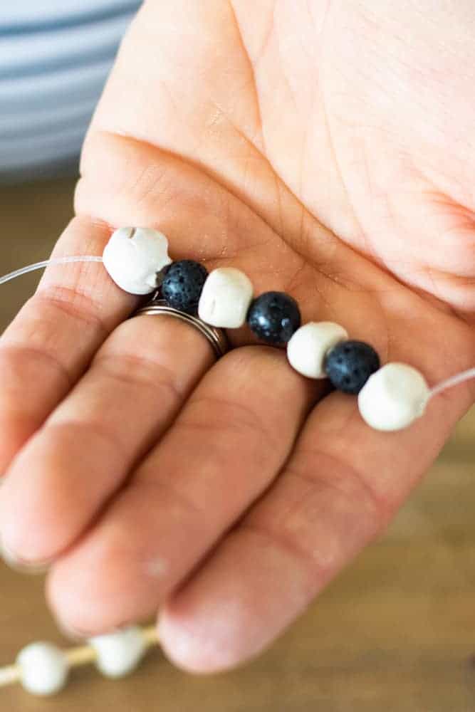 Bracelet with essential oils on clear string and homemade air dry clay beads on toothpick in background