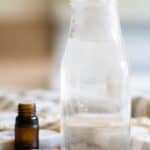 glass container of mouthwash with essential oil bottle next to it