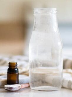 glass container of mouthwash with essential oil bottle next to it