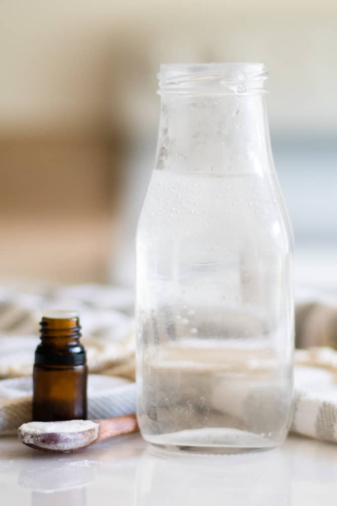 Essential oil mouthwash bottle with mouthwash ingredients on the table.