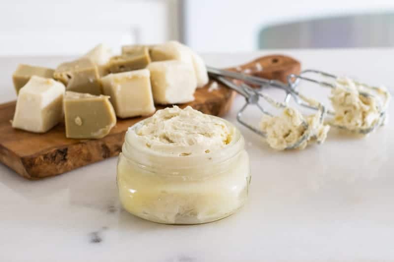 stretch mark cream in mason jar with hand mixer and chopped shea butter in background