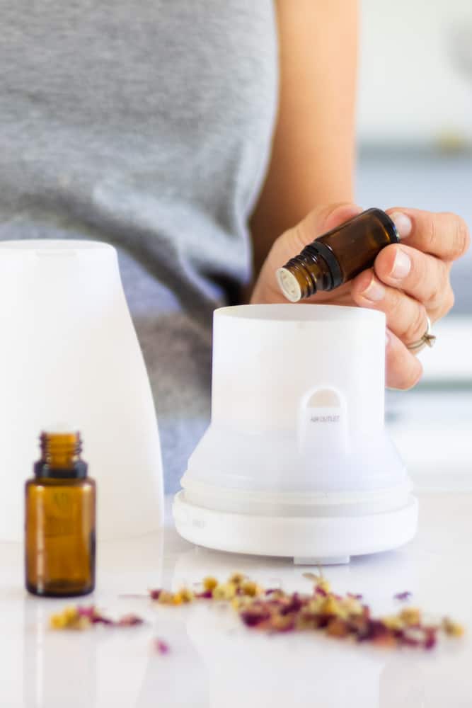 Adding essential oils to a white diffuser.