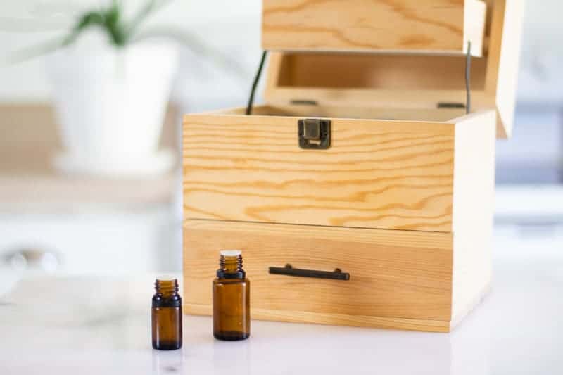 amber colored essential oil bottles in front of storage box on a white marble table top