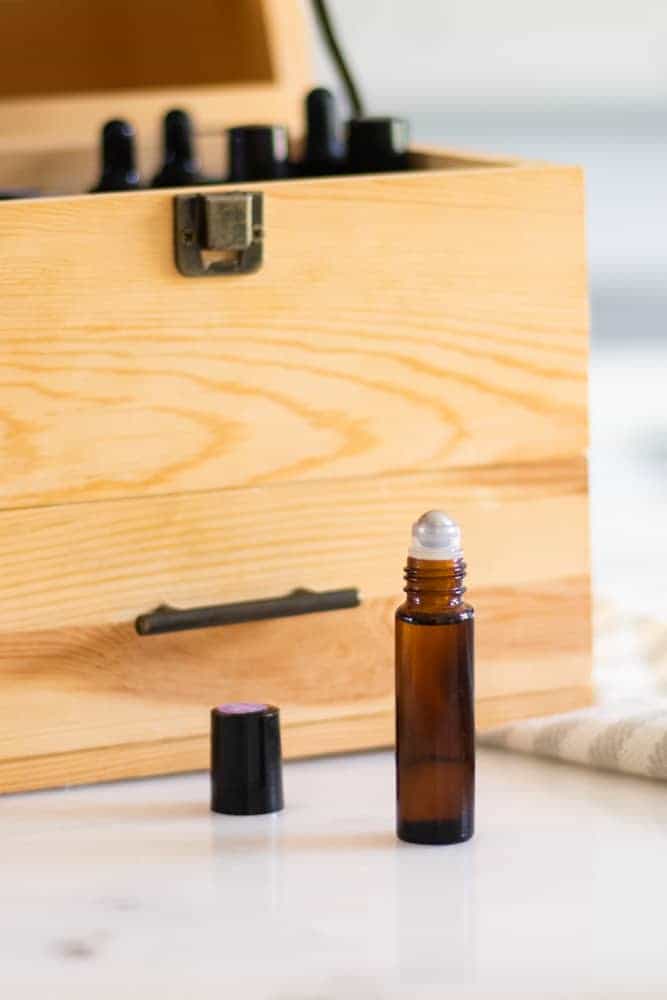 bergamot roller bottle for hair in front of custom wooden oil storage box