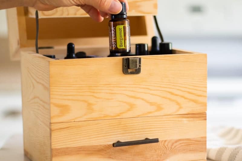 pulling essential oils from wooden storage box.