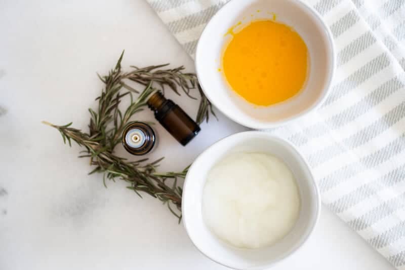 Egg yolk deep conditioner treatment in white bowl with green sprigs and essential oil bottles.