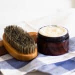 beard conditioner in amber colored container on blue checkered tea towel.