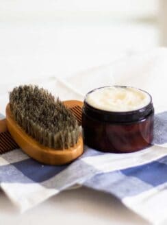 beard conditioner in amber colored container on blue checkered tea towel.