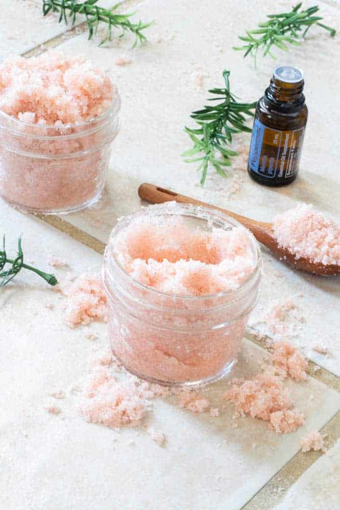 DIY foot scrub on a white tile floor with peppermint essential oil.