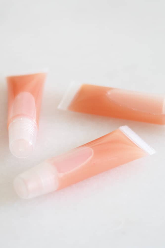 three pink diy lip gloss tubes on white marble