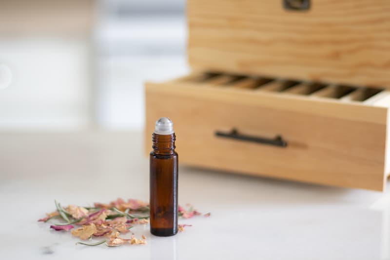 oils for acne in amber colored roller bottle in front of wooden box