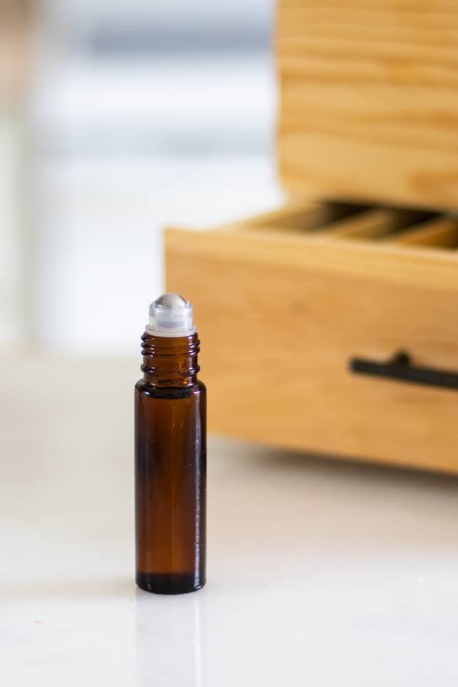 essential oil blend for acne in 10ml roller bottle on white table top with custom wooden box in background