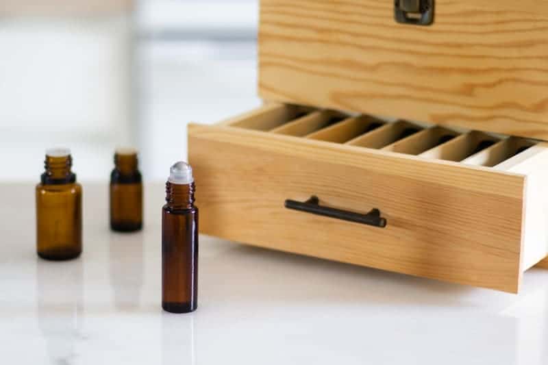 essential oils for skin imperfections in roller bottle and drip bottles in front of wooden oil box
