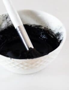 White bowl with diy charcoal mask in it.