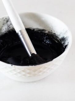 White bowl with diy charcoal mask in it.